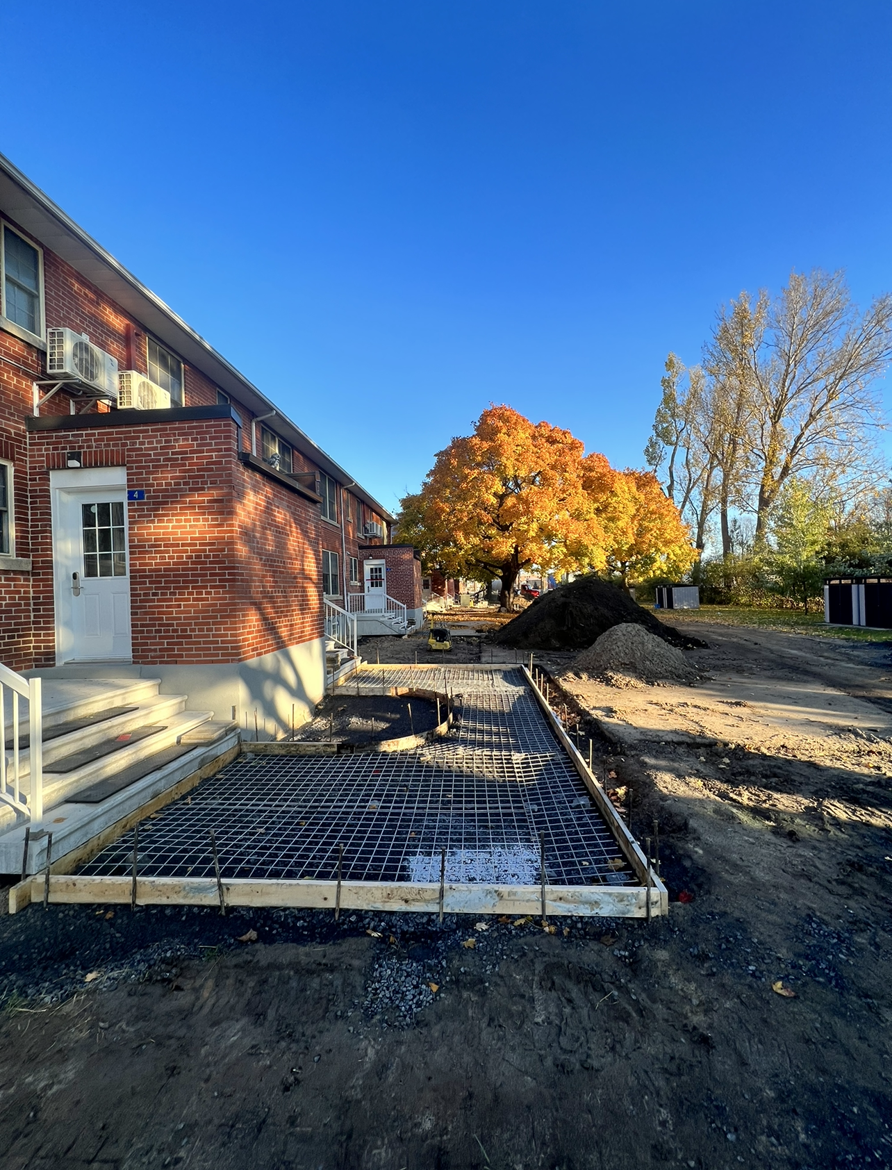 Un bâtiment en brique avec une passerelle en béton en construction devant.