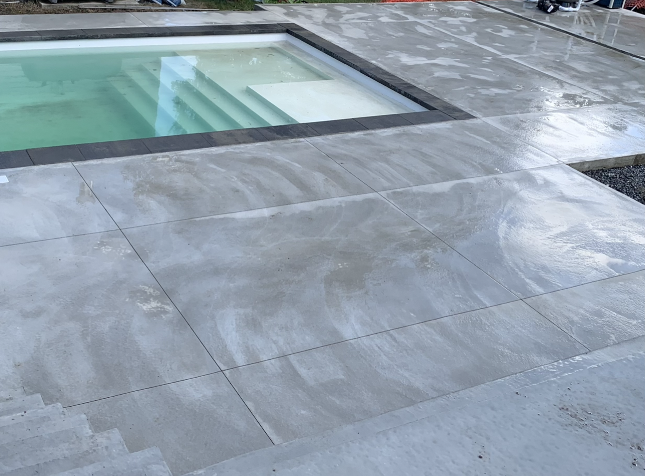 Une piscine est entourée d'un patio en béton