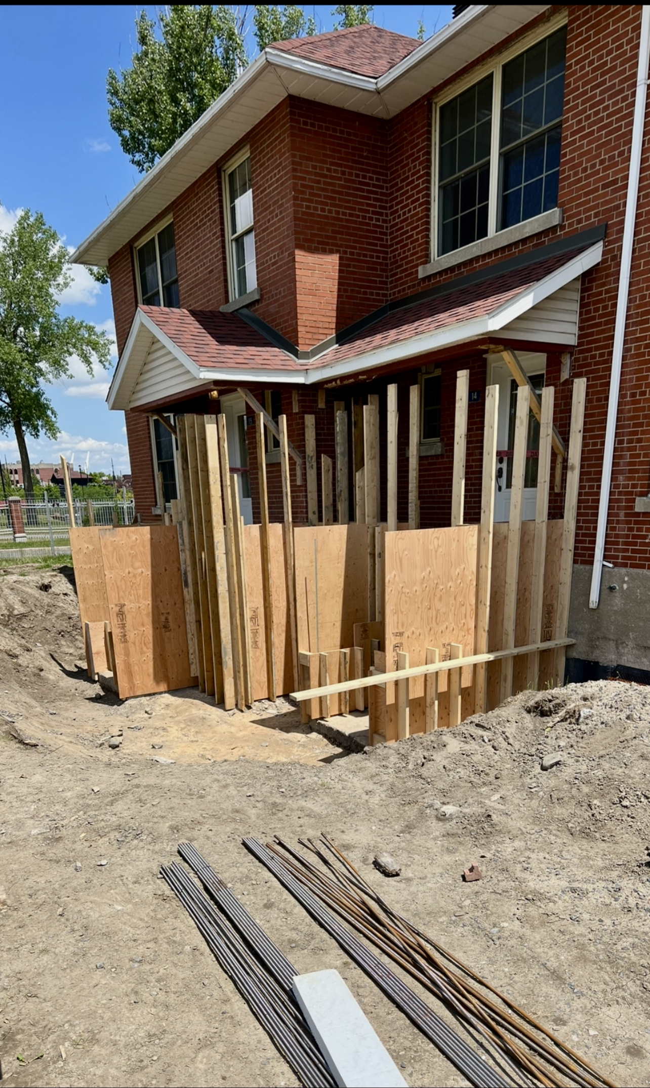 Une maison en brique est en cours de rénovation et une clôture en bois est en cours de construction.