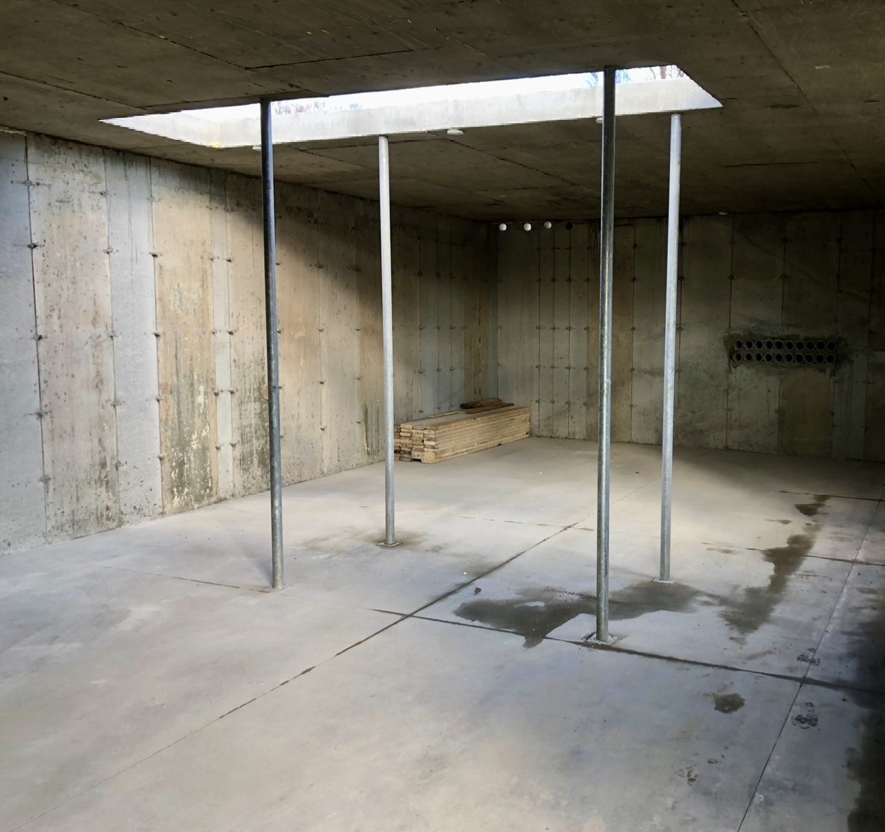 Un sous-sol vide avec des murs en béton et des poteaux métalliques