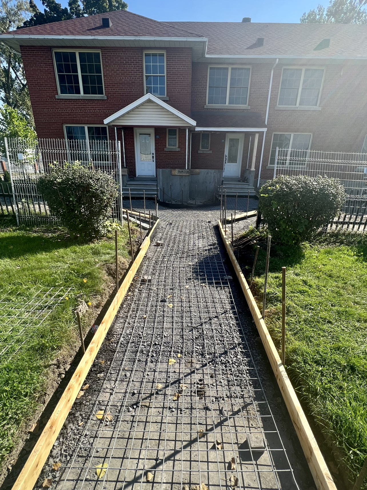 Une passerelle est en cours de construction devant une maison en brique.