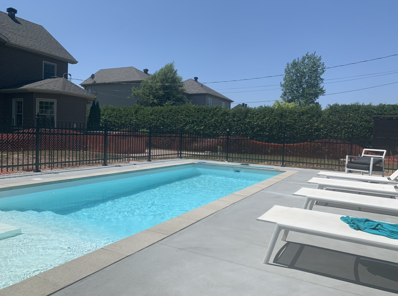 Une grande piscine entourée de transats et d'une clôture.