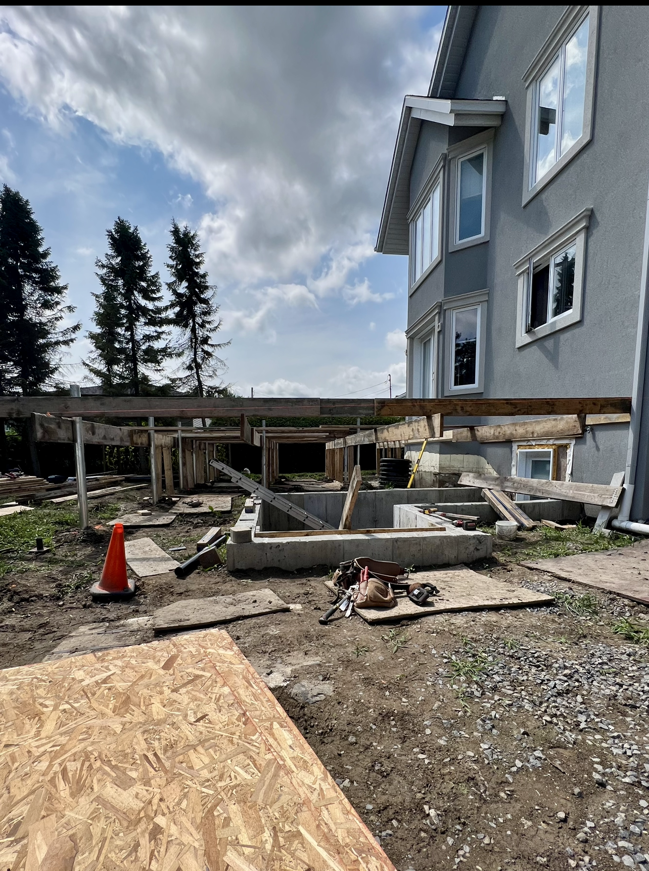 Une grande maison est en construction sur pilotis dans une cour.
