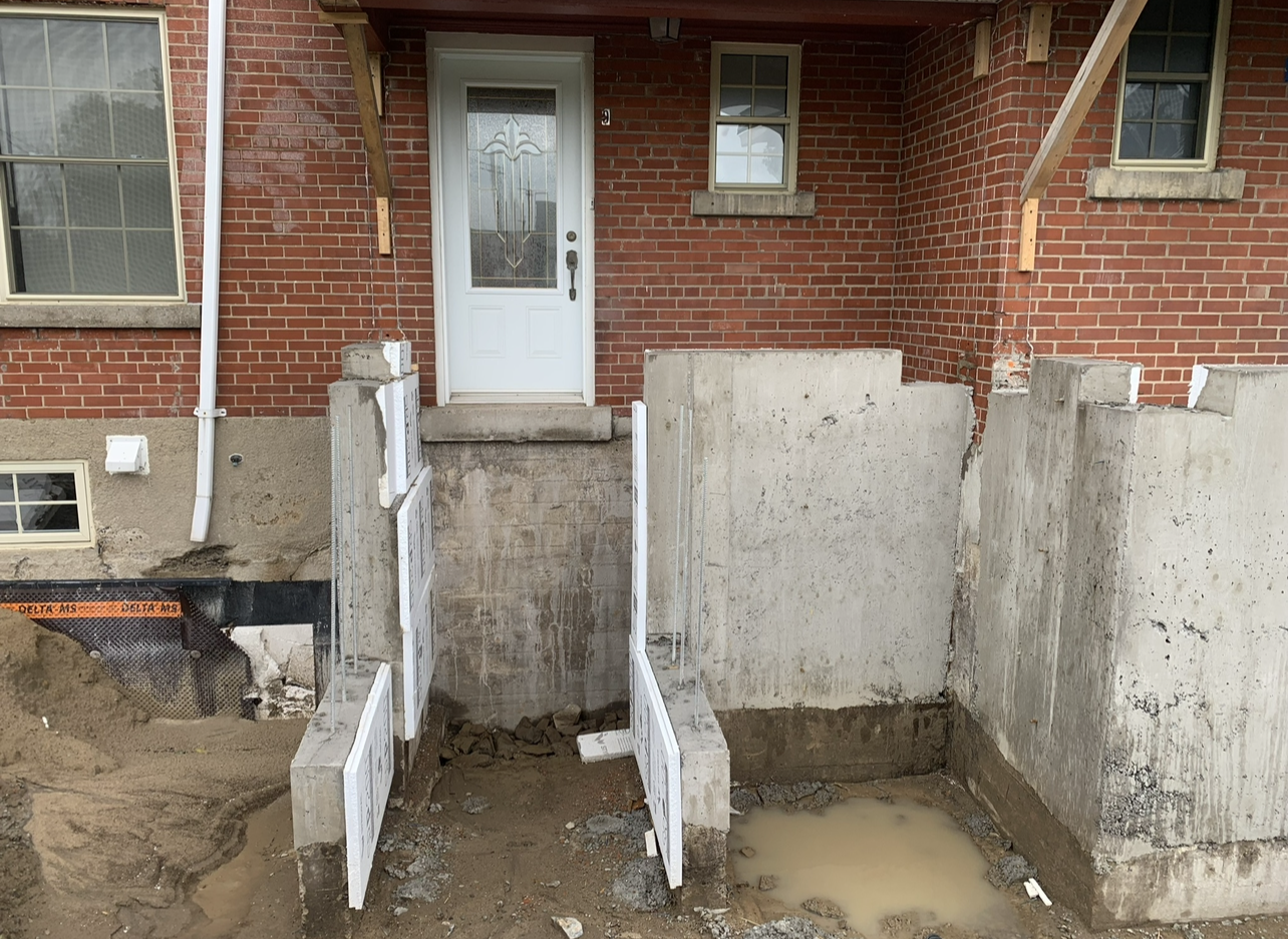 Une maison en brique avec une porte blanche est en cours de rénovation