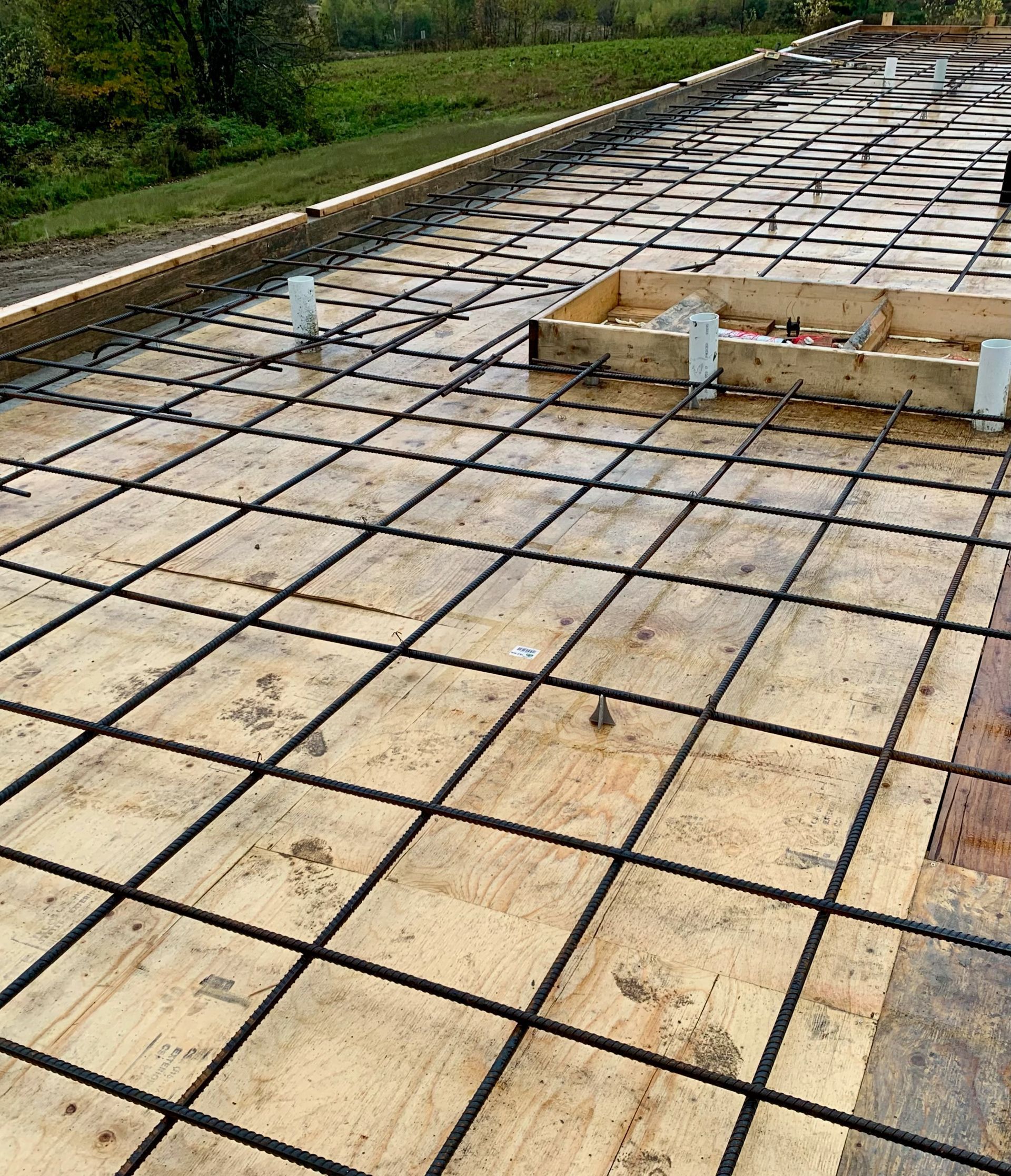 Une fondation en béton est en cours de construction sur un plancher en bois.