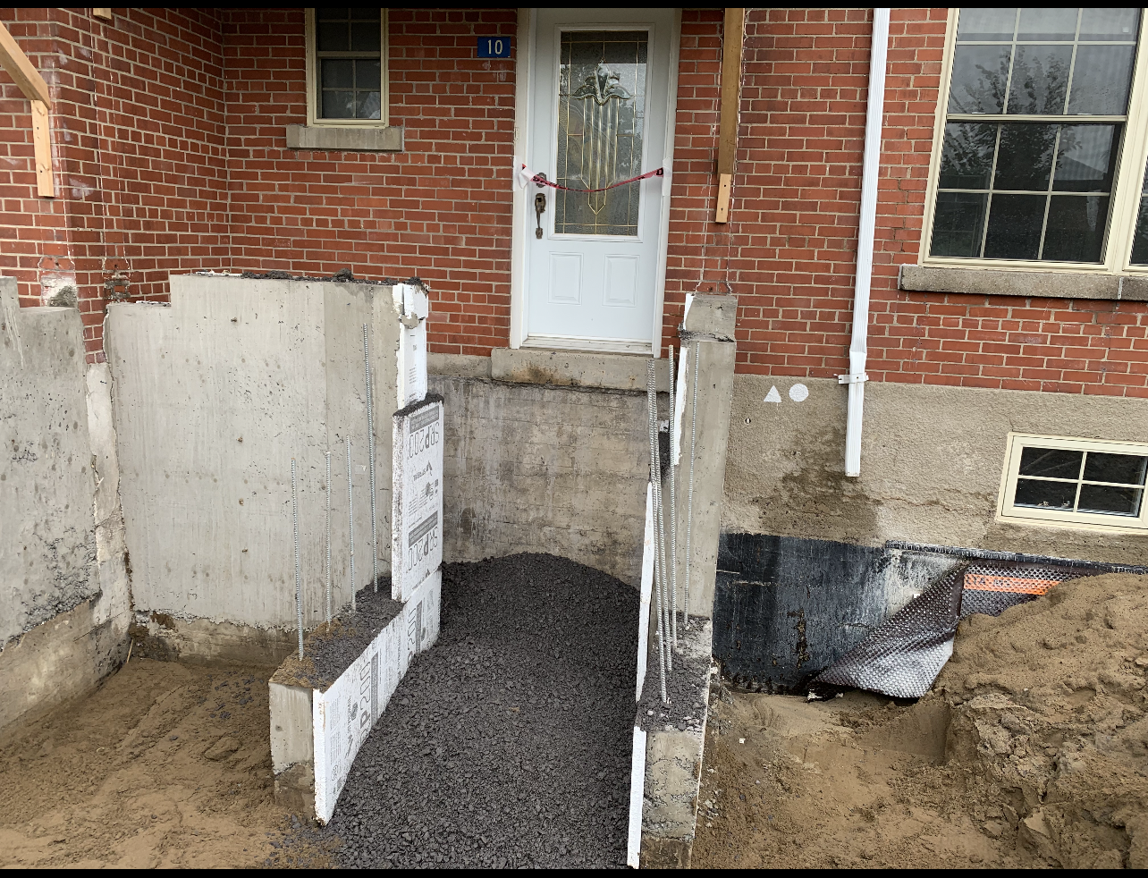Une maison en brique avec un trou dans le sol devant.