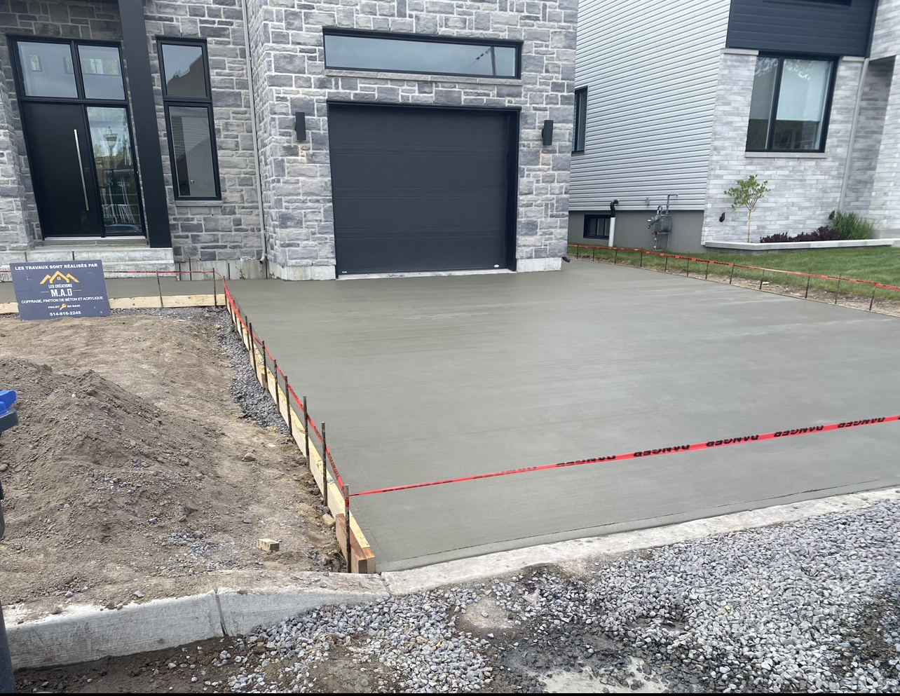 Une allée en béton est en cours de construction devant une maison.