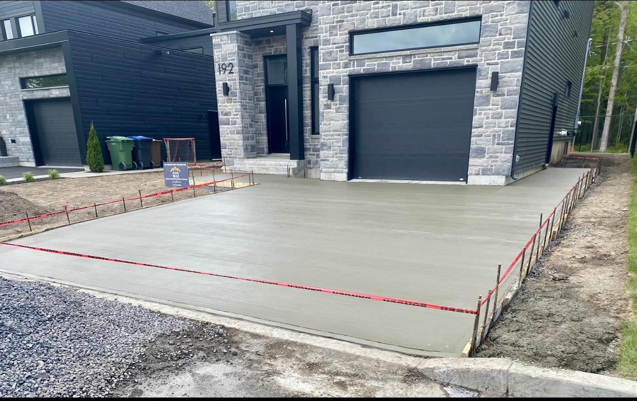 Une allée en béton est en cours de construction devant une maison.