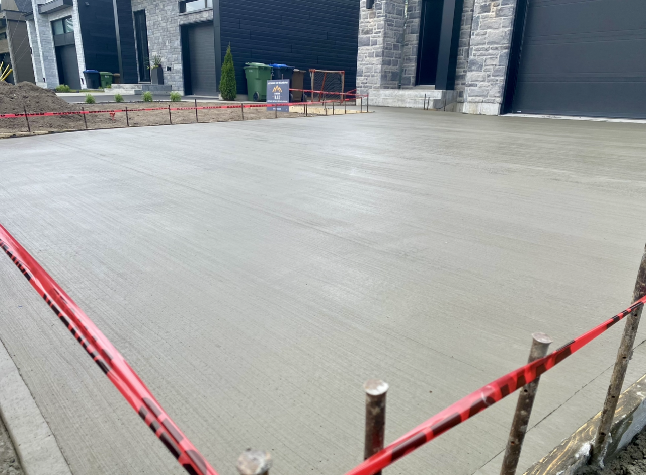 Une allée en béton est en cours de construction devant une maison.