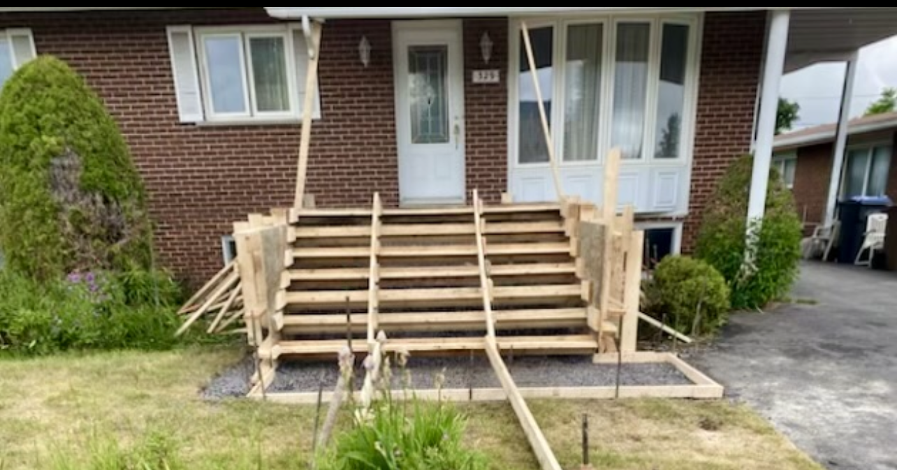 Une maison en brique avec des marches en bois en construction devant.