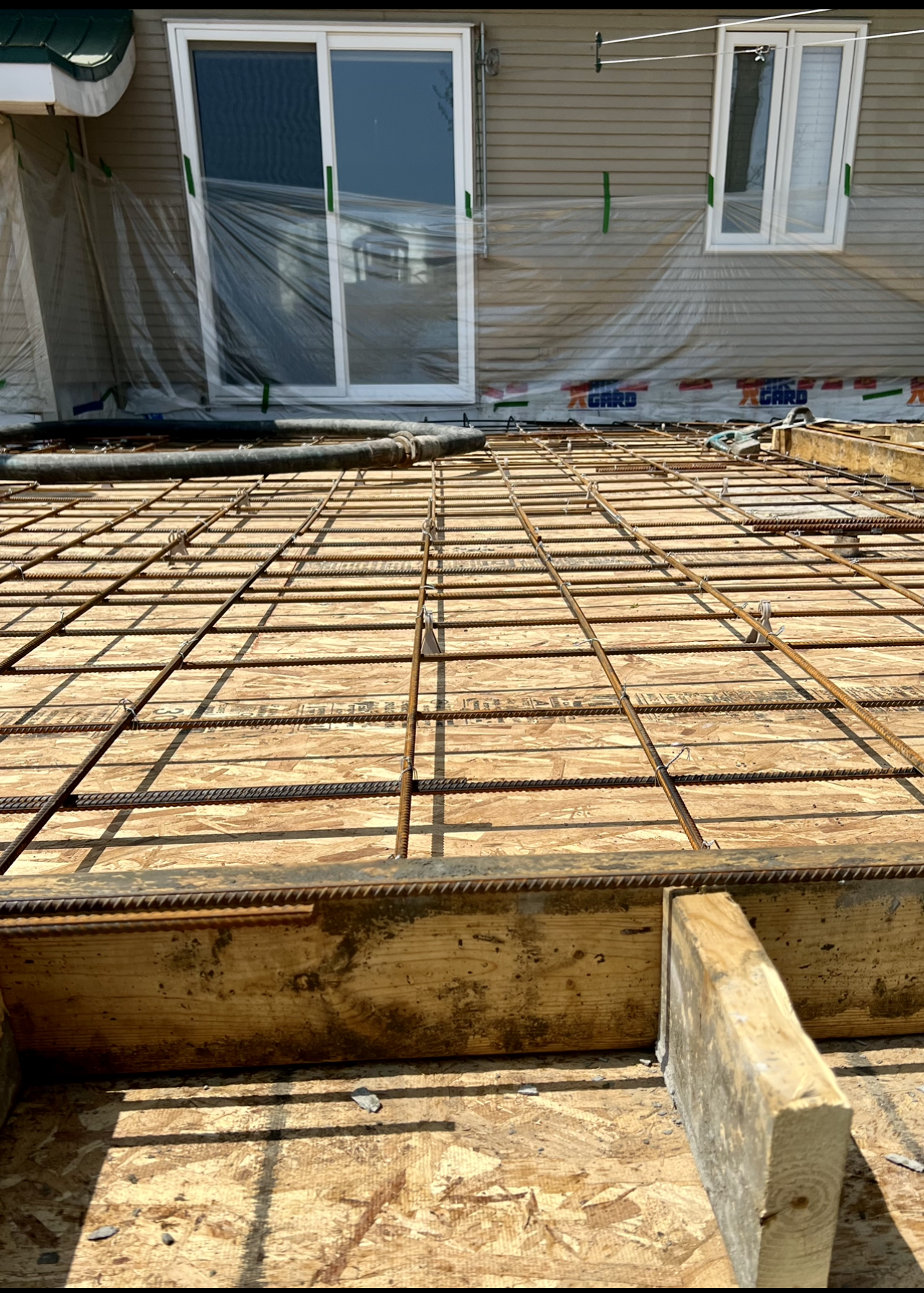 Une terrasse en béton est en cours de construction devant une maison.
