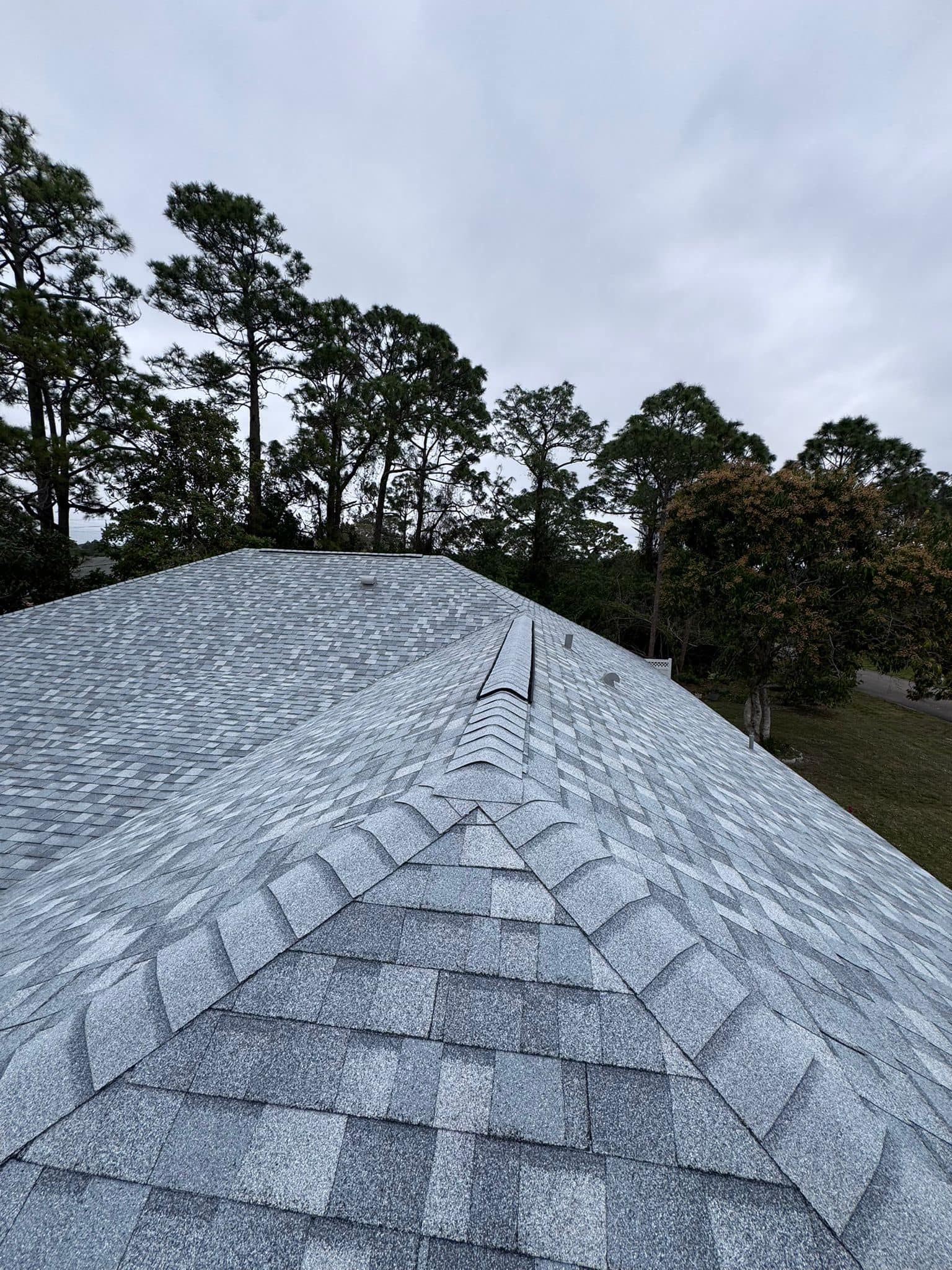 A roof with a lot of shingles on it and trees in the background.