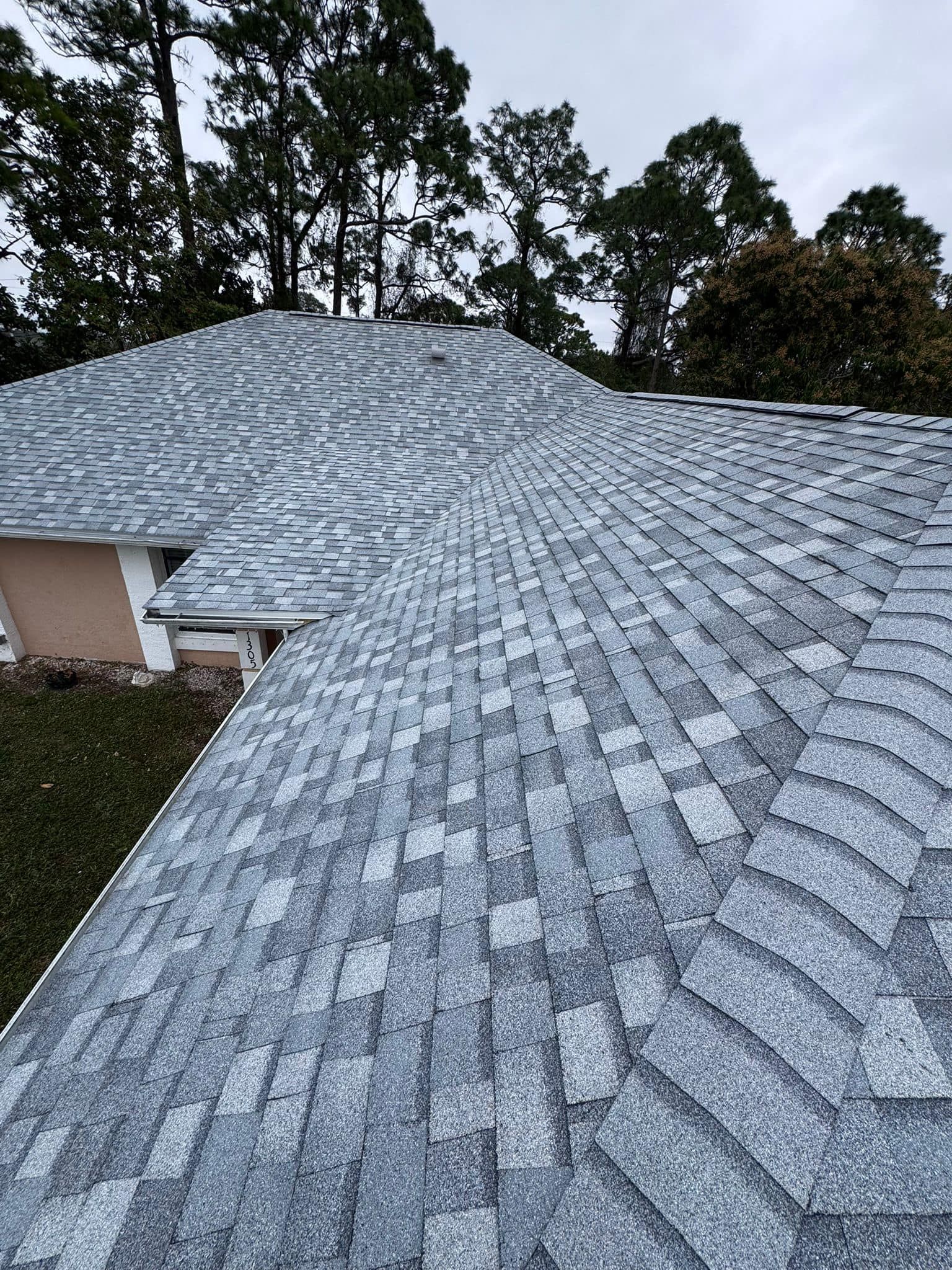 A roof with a lot of shingles on it and trees in the background.
