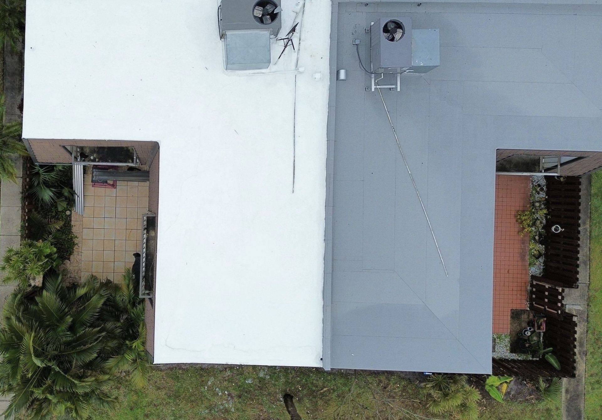 An aerial view of a house with a white roof and a gray roof.