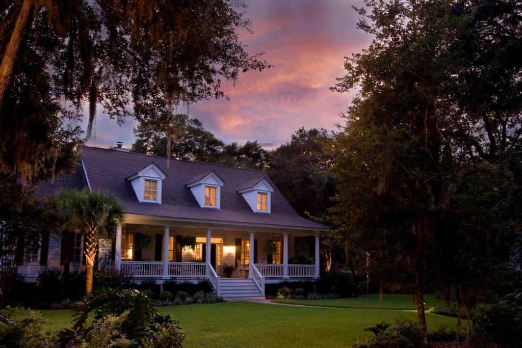 A house with a large porch is lit up at night.