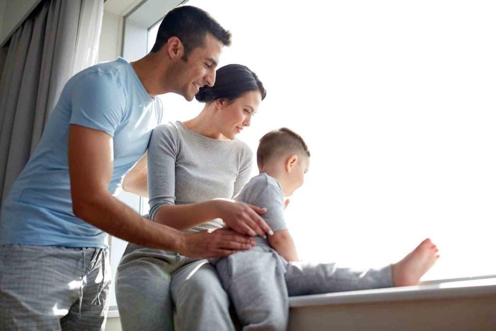 A family is sitting on a window sill looking out the window.