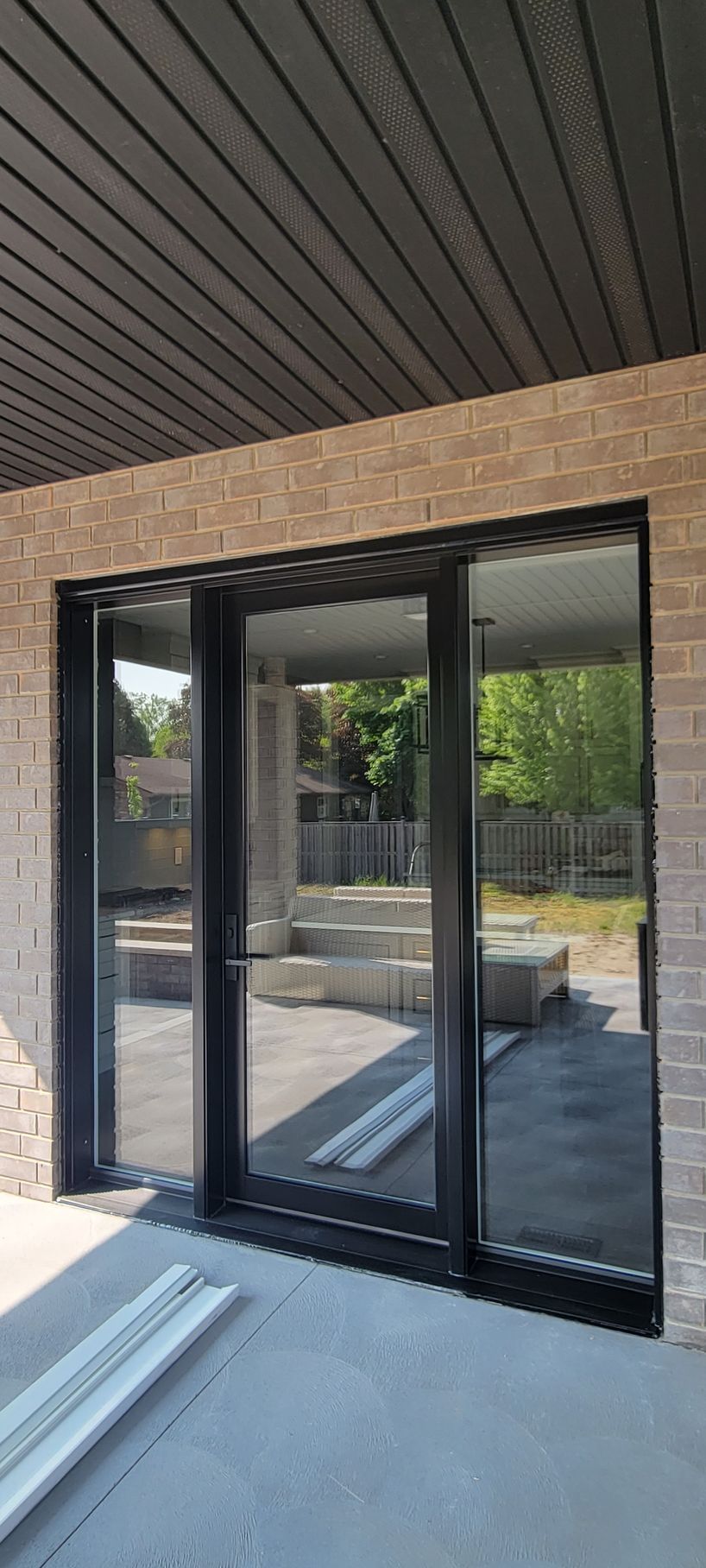 A brick building with sliding glass doors and a black frame.