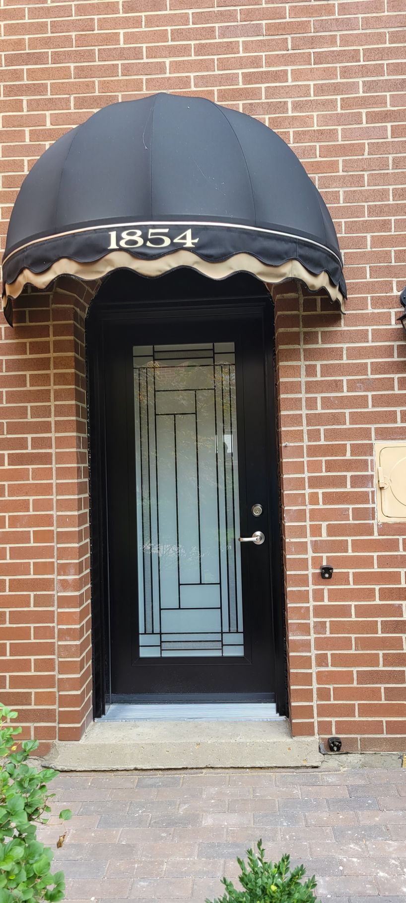 A brick building with a black awning over the door.