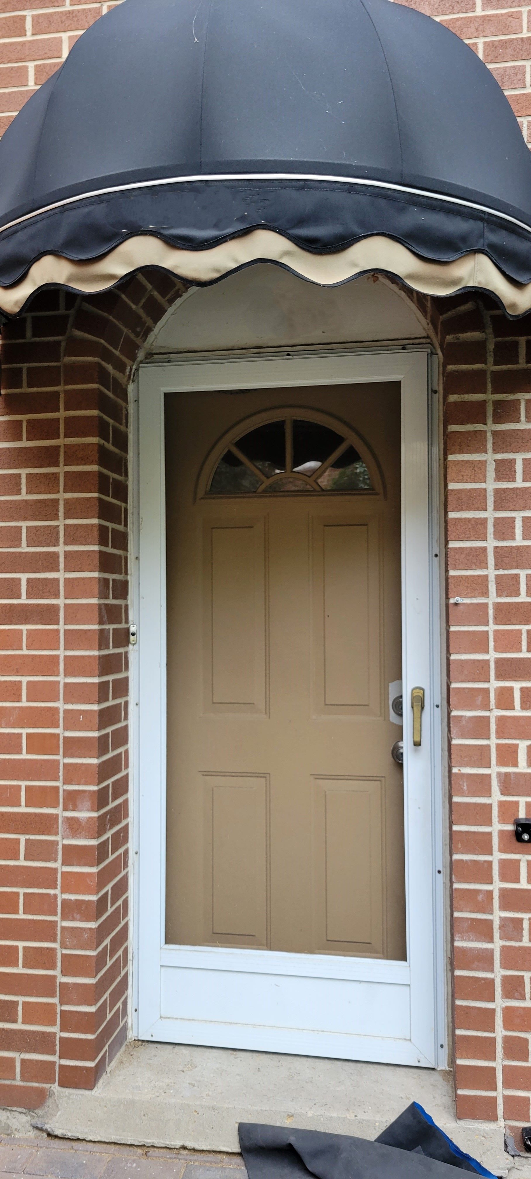 A door with a black awning over it is on a brick building.