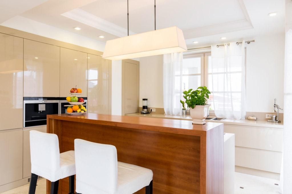 A kitchen with a wooden island and two white chairs.