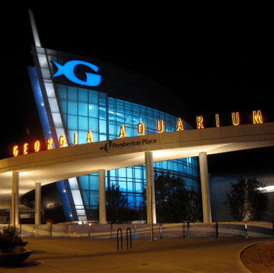 Georgia Aquarium entrance at night, lit with blue and orange lights. The sign reads