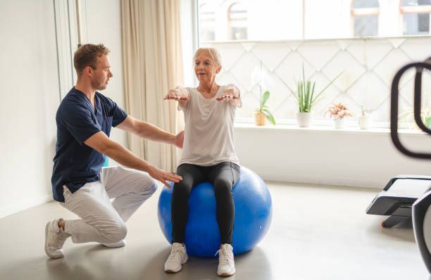 A young physiotherapist guiding an elderly woman through rehabilitation exercises | PhysioPhix