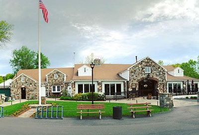 Stone building with US flag, green lawn, benches, and outdoor seating.