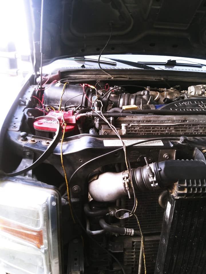 Open hood of a diesel truck engine with exposed wires, battery, and intake.
