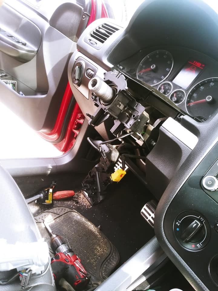 Interior car dashboard disassembled, tools visible, steering column exposed.