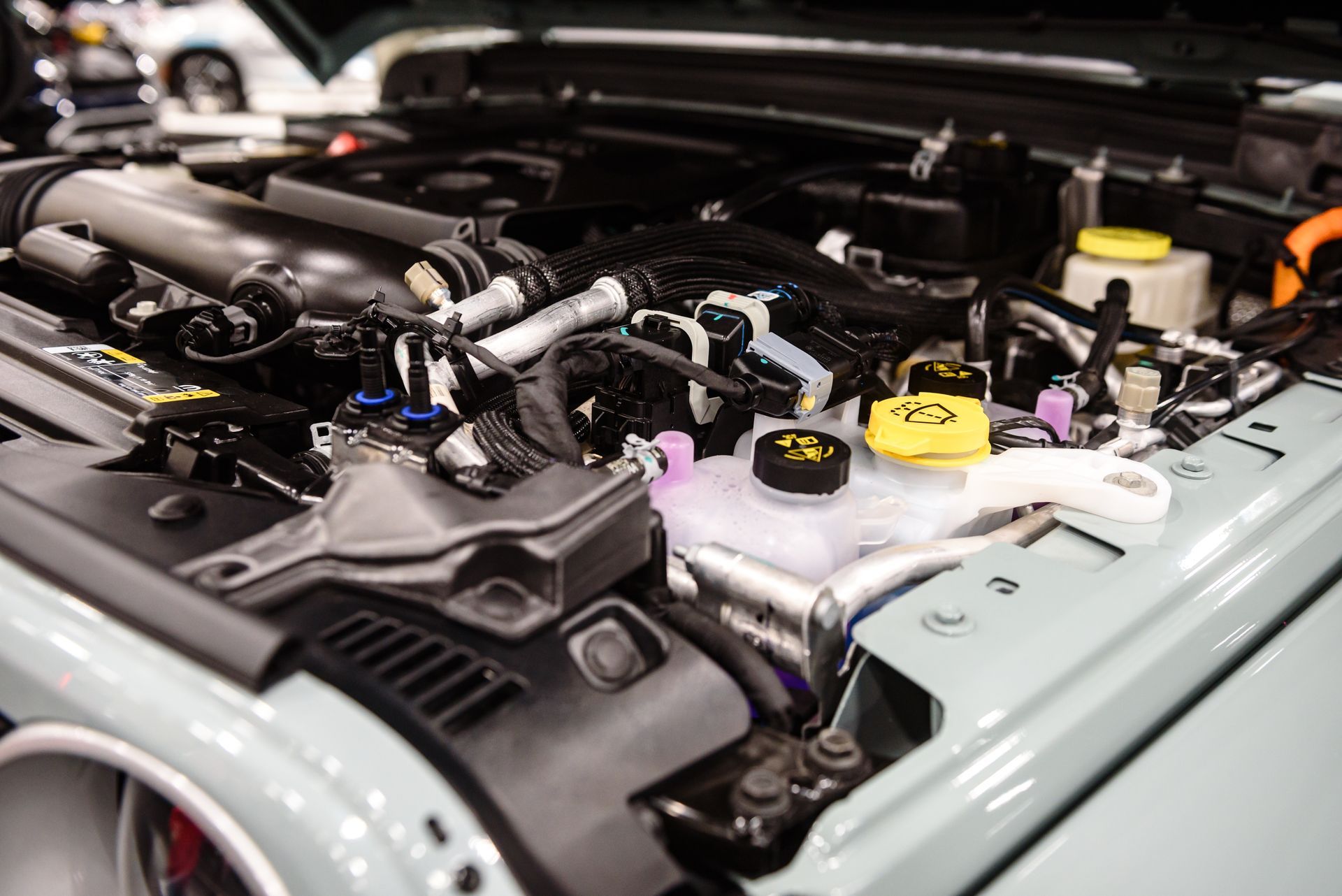Open engine bay of a Jeep, featuring black components, various tubes, and colored caps.