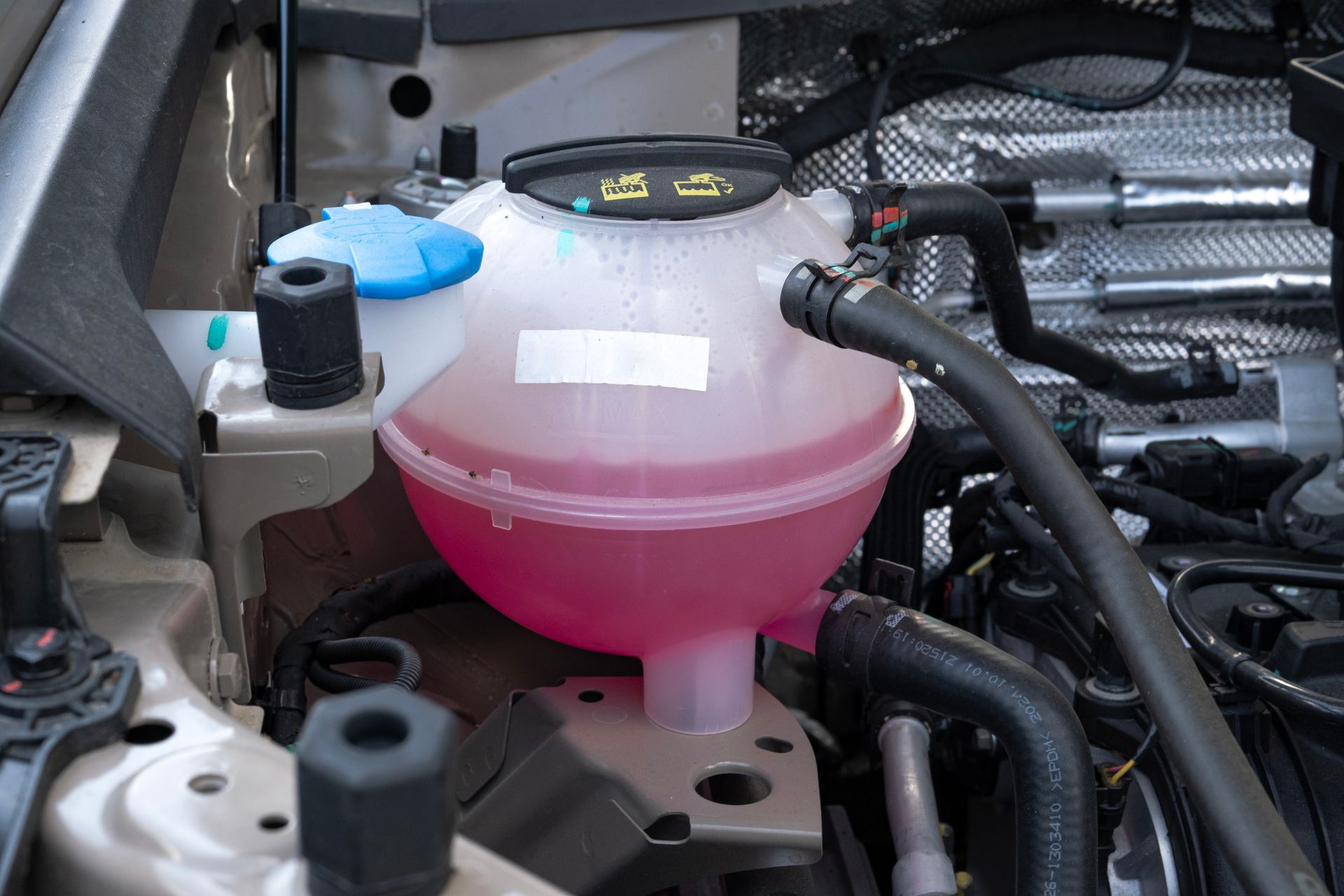 Coolant reservoir in an engine bay filled with pink fluid.