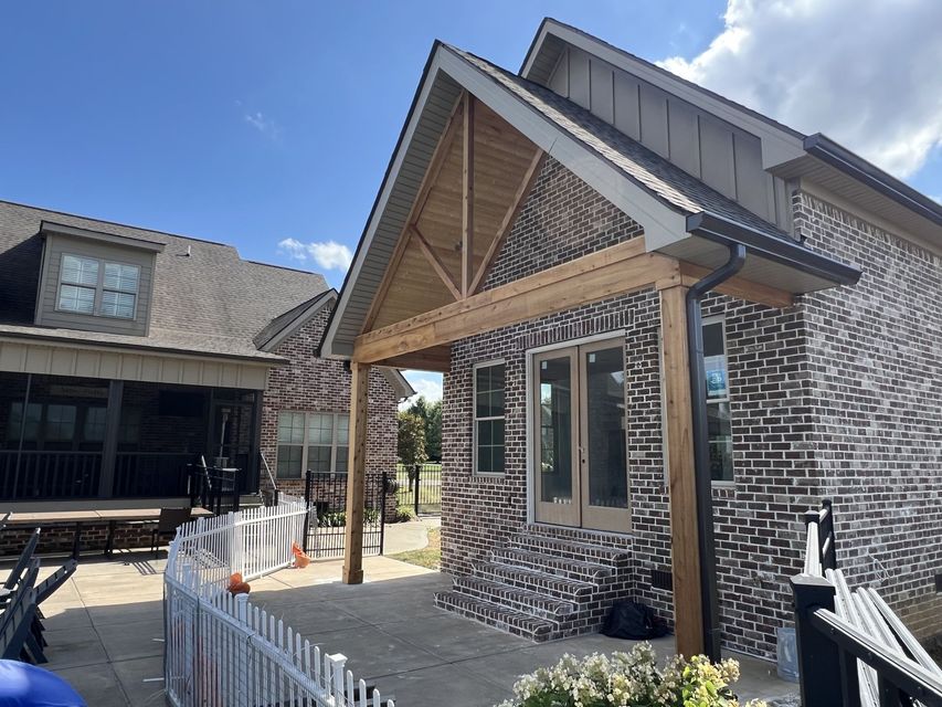 A brick house with a wooden porch and a white picket fence.