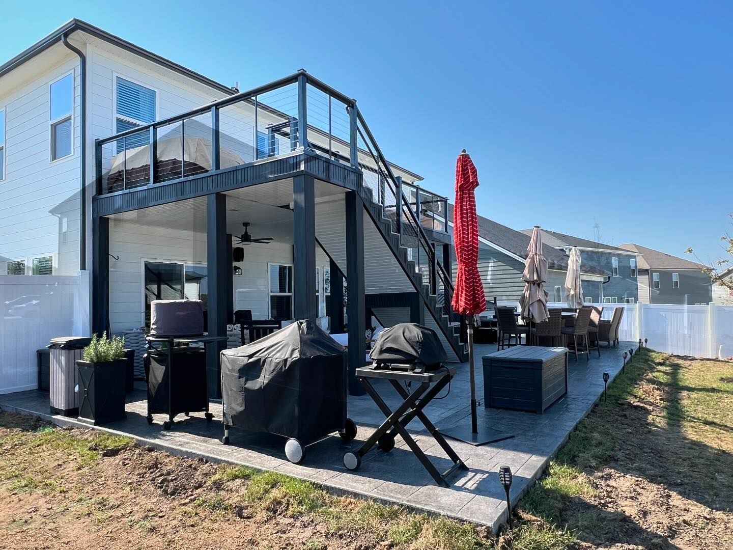 The backyard of a house with a large deck and stairs leading up to it.