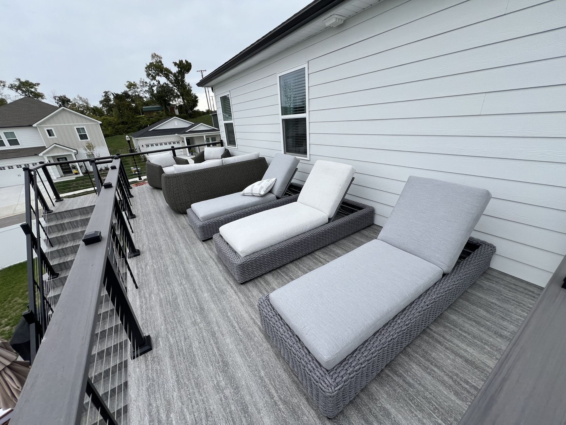 There are a lot of lounge chairs on the deck of a house.