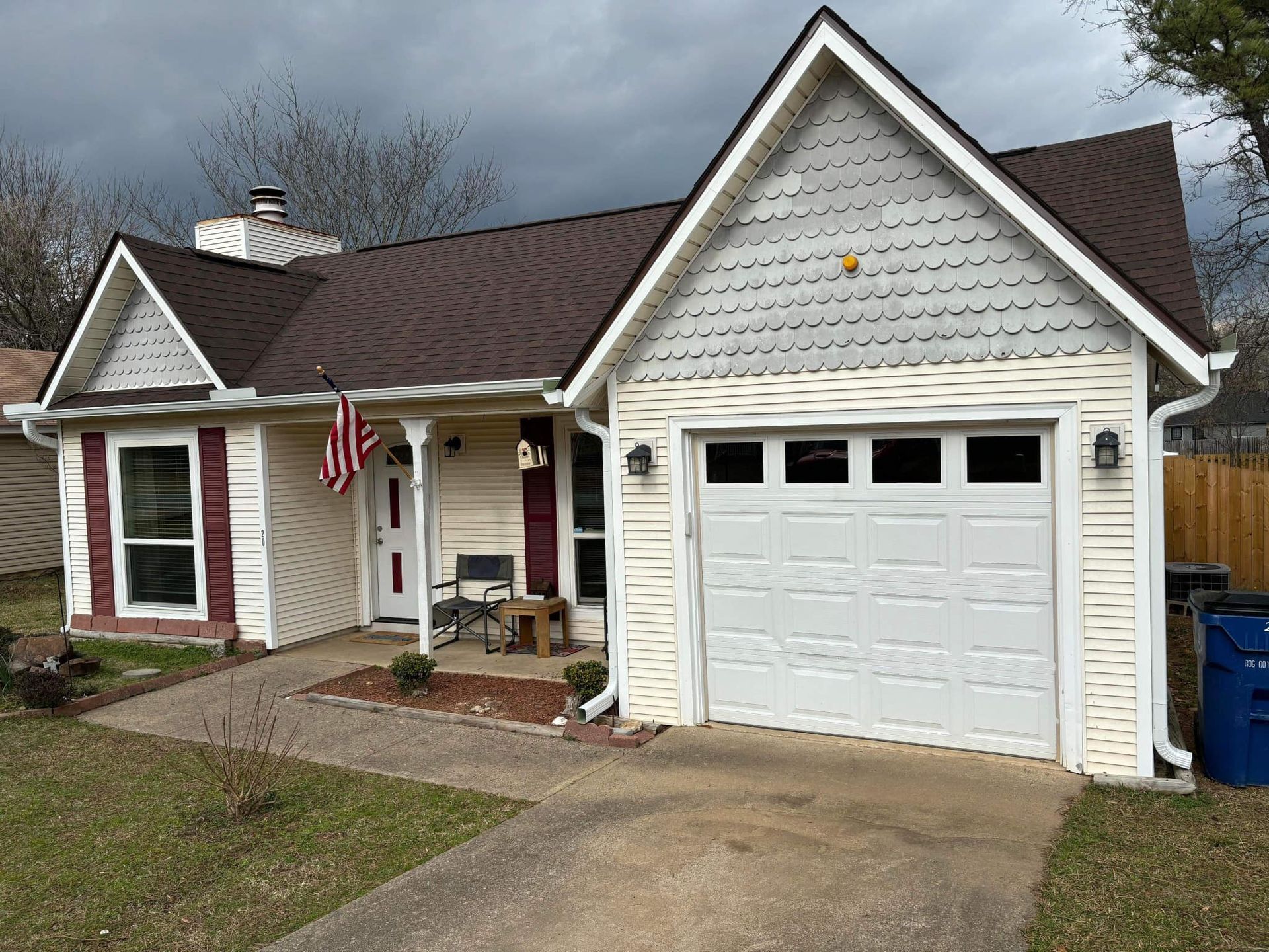 A small white house with a brown roof and a white garage door.
