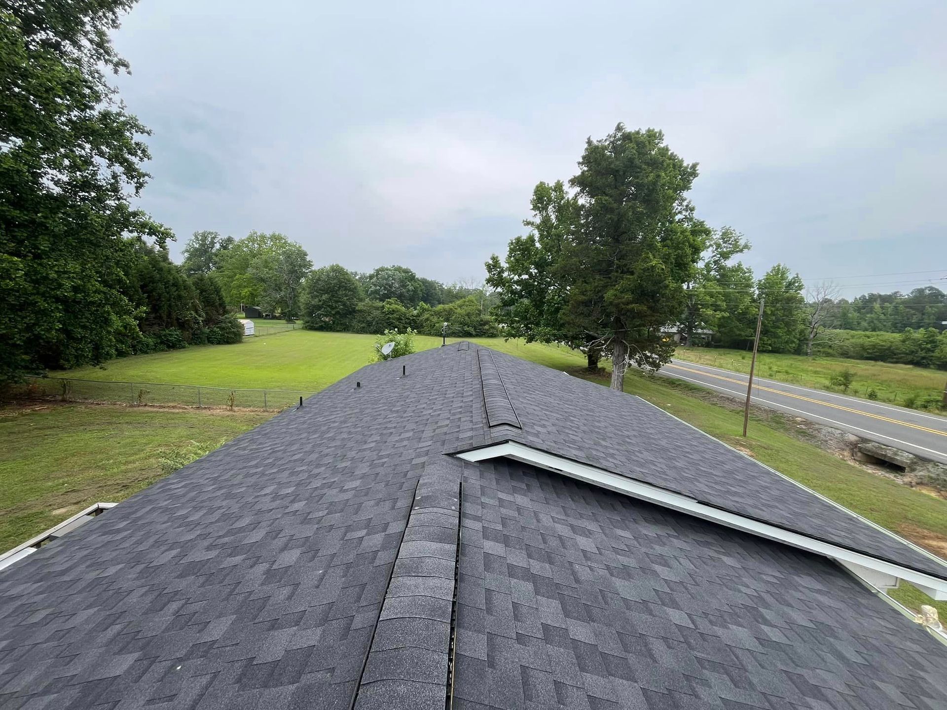 A roof with a lot of shingles on it and a road in the background.