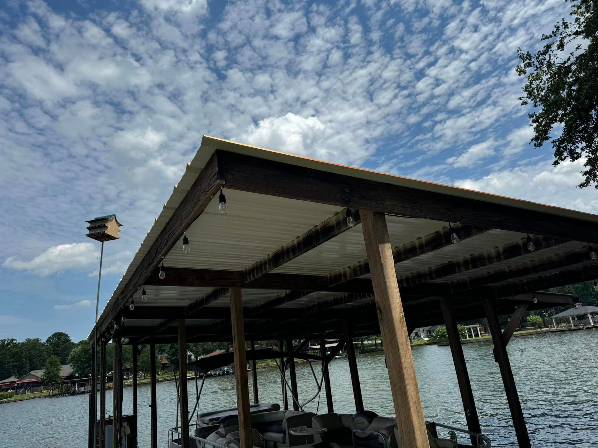 A boat is docked under a covered dock on a lake.