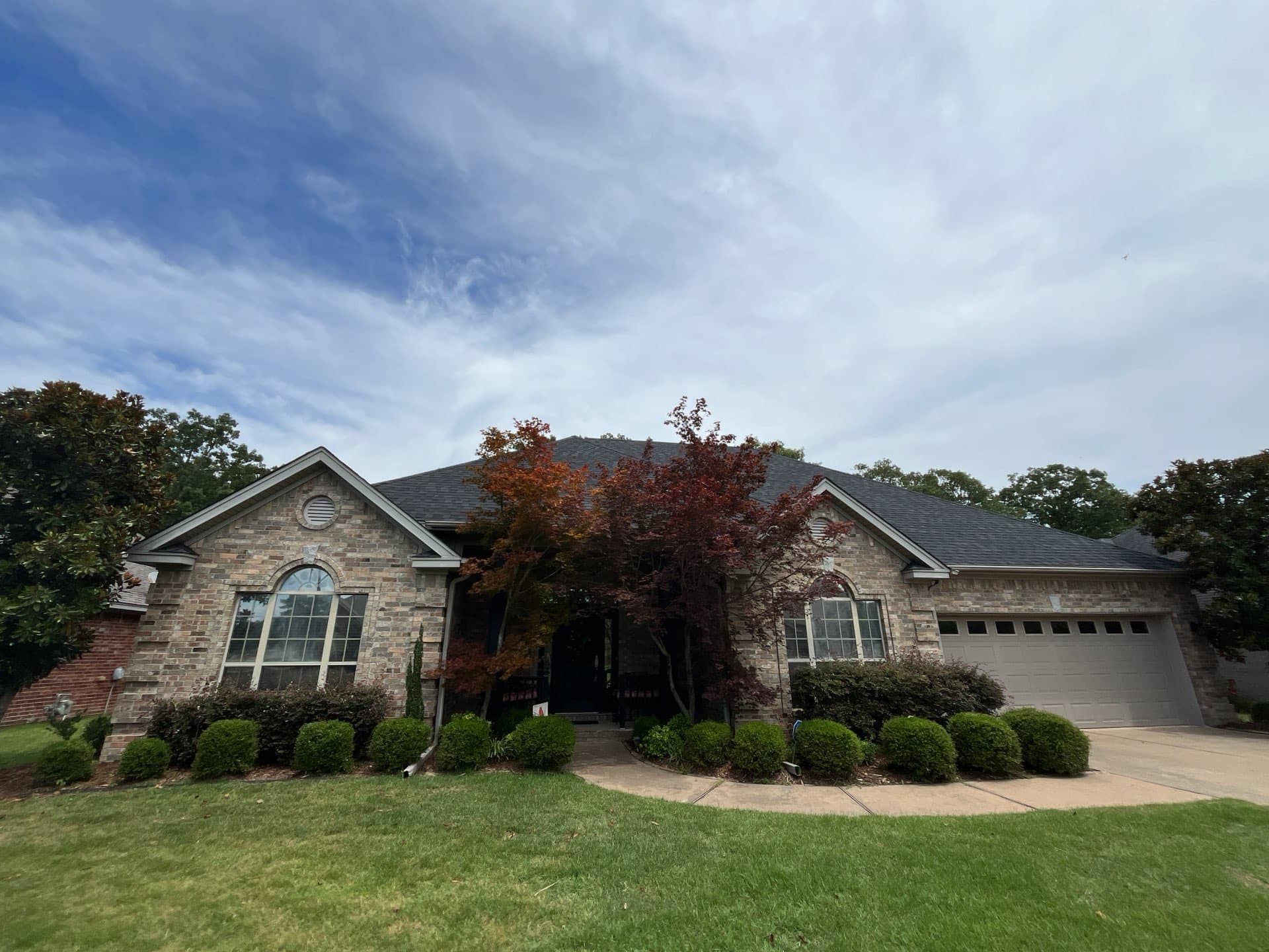 A large brick house with a lush green lawn and trees in front of it.