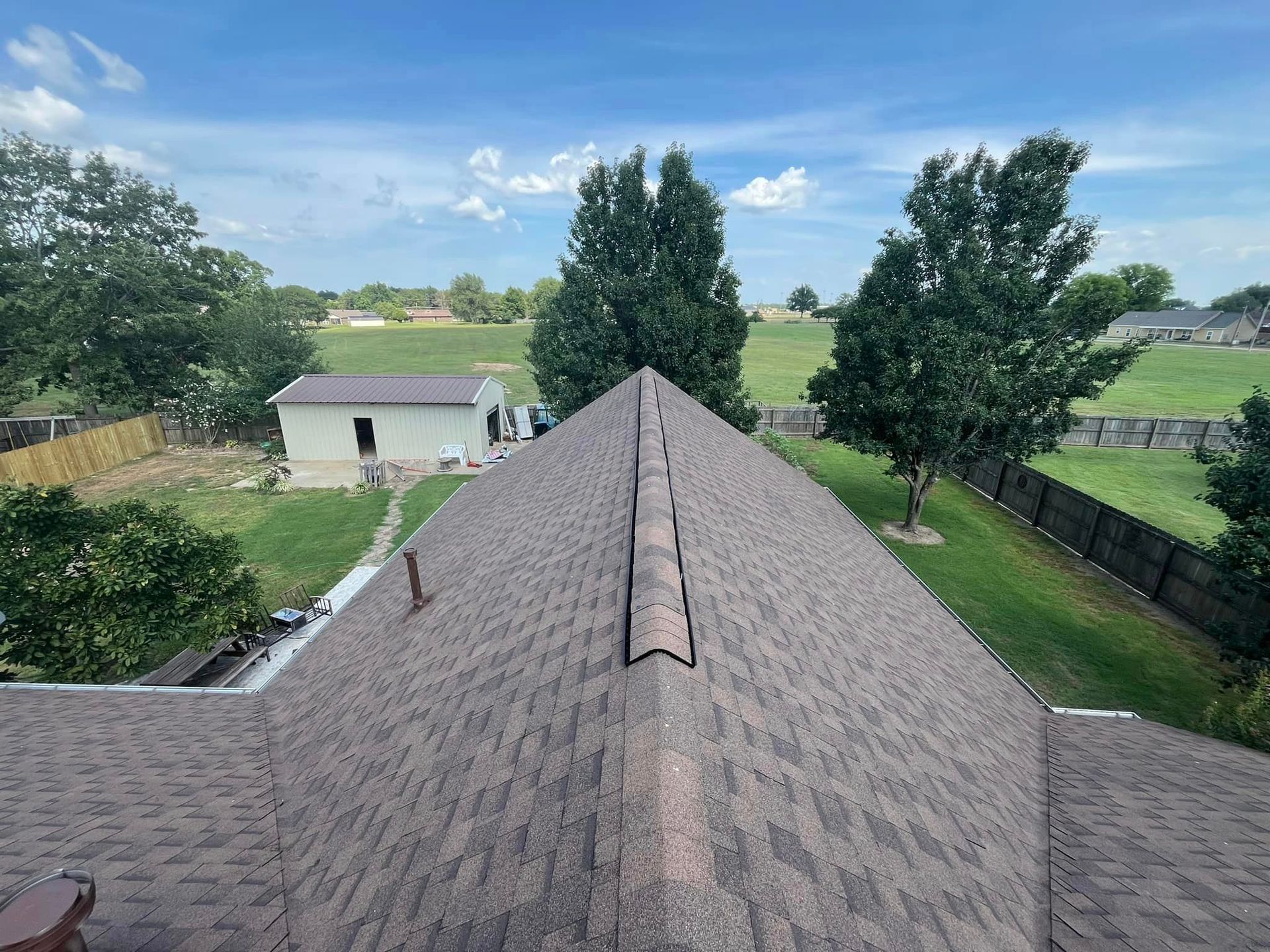 An aerial view of a roof of a house with trees in the background.