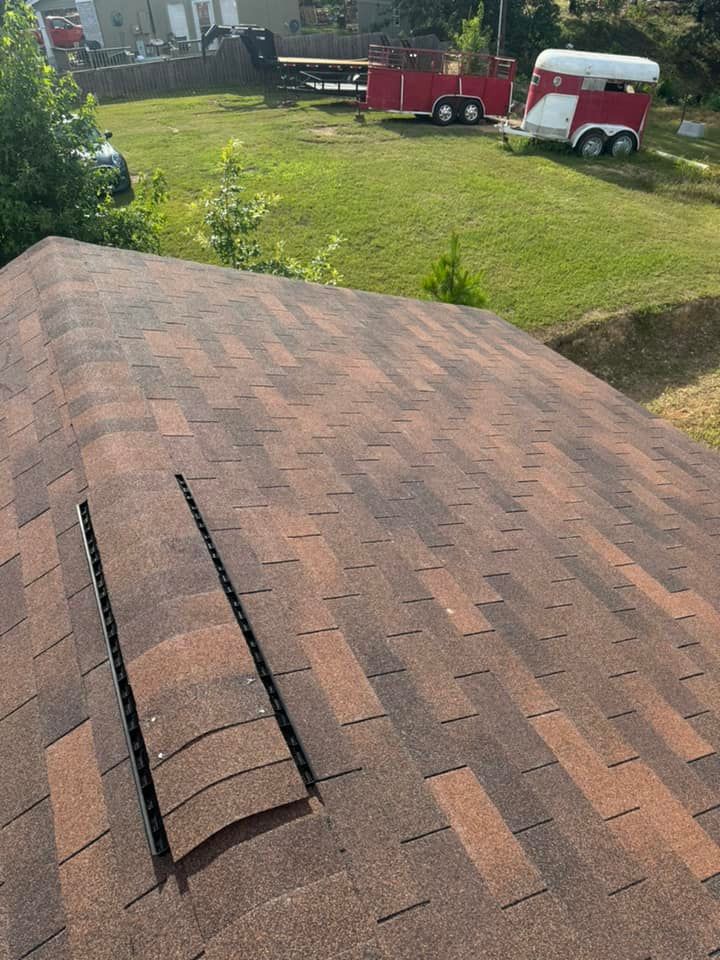 A horse trailer is parked on the grass next to a roof.