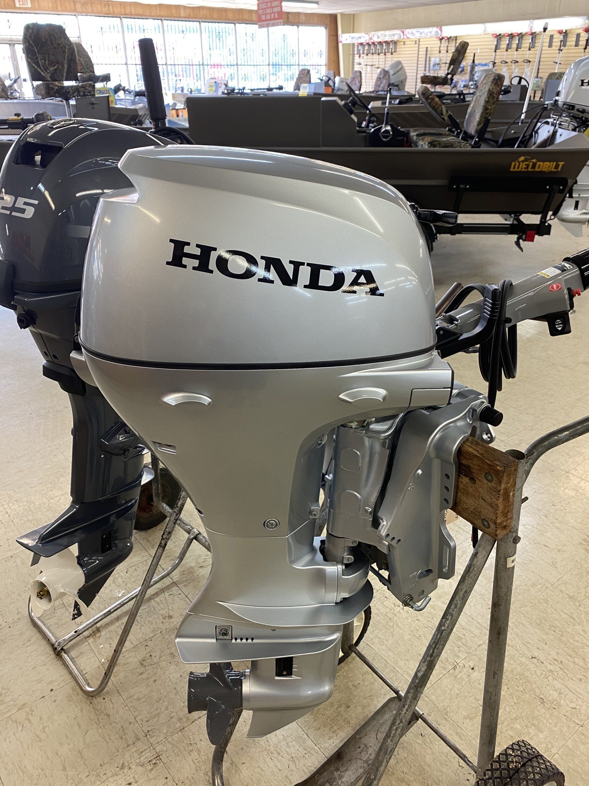 A honda outboard motor is sitting on a cart in a store.