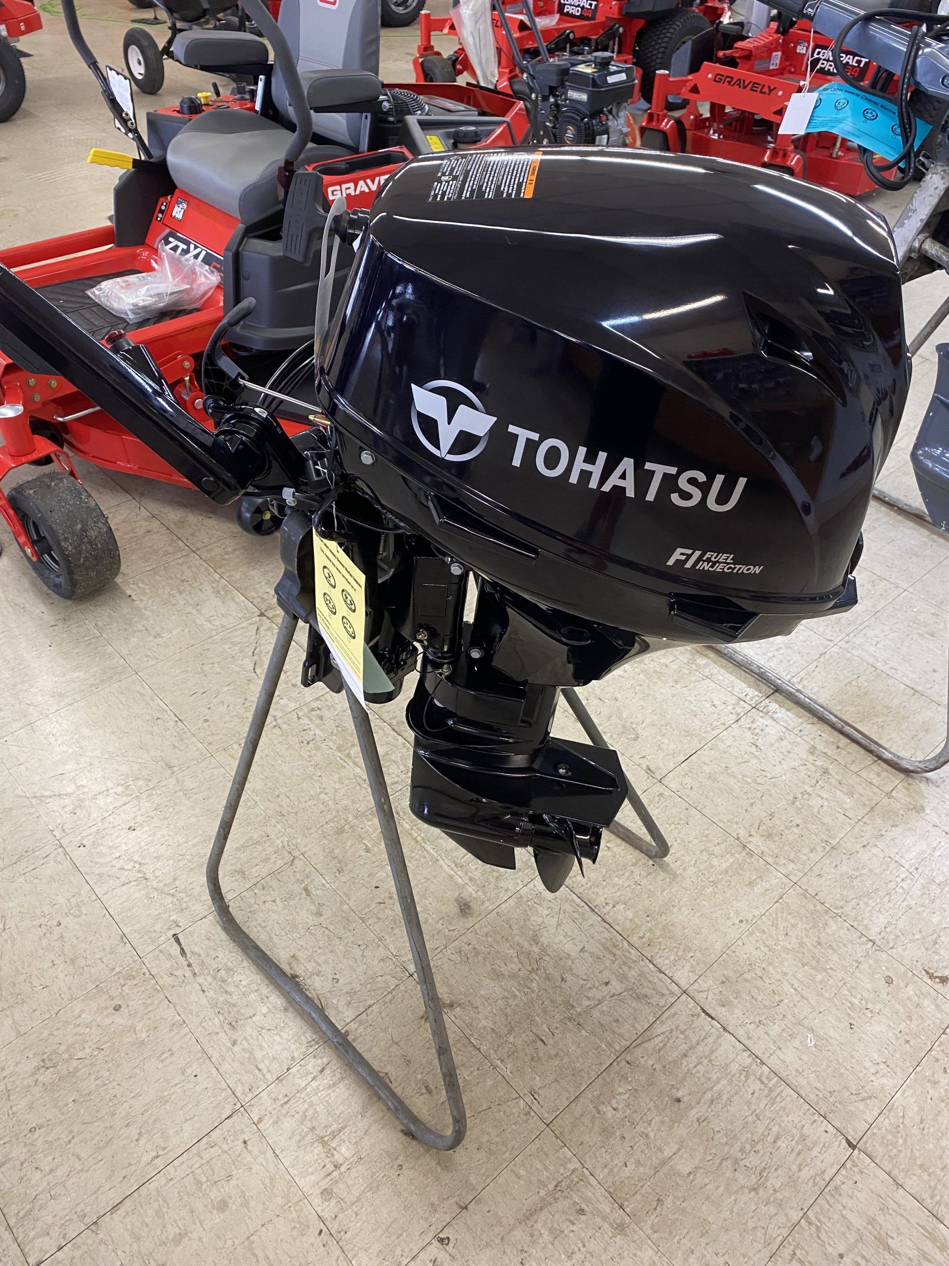 A tohatsu outboard motor is sitting on a stand in a store.