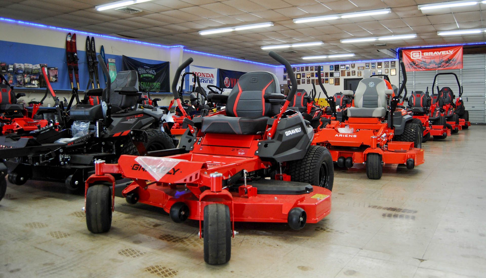 A row of red lawn mowers are lined up in a garage.