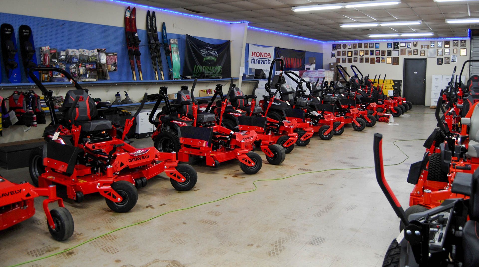 A row of red lawn mowers are lined up in a store