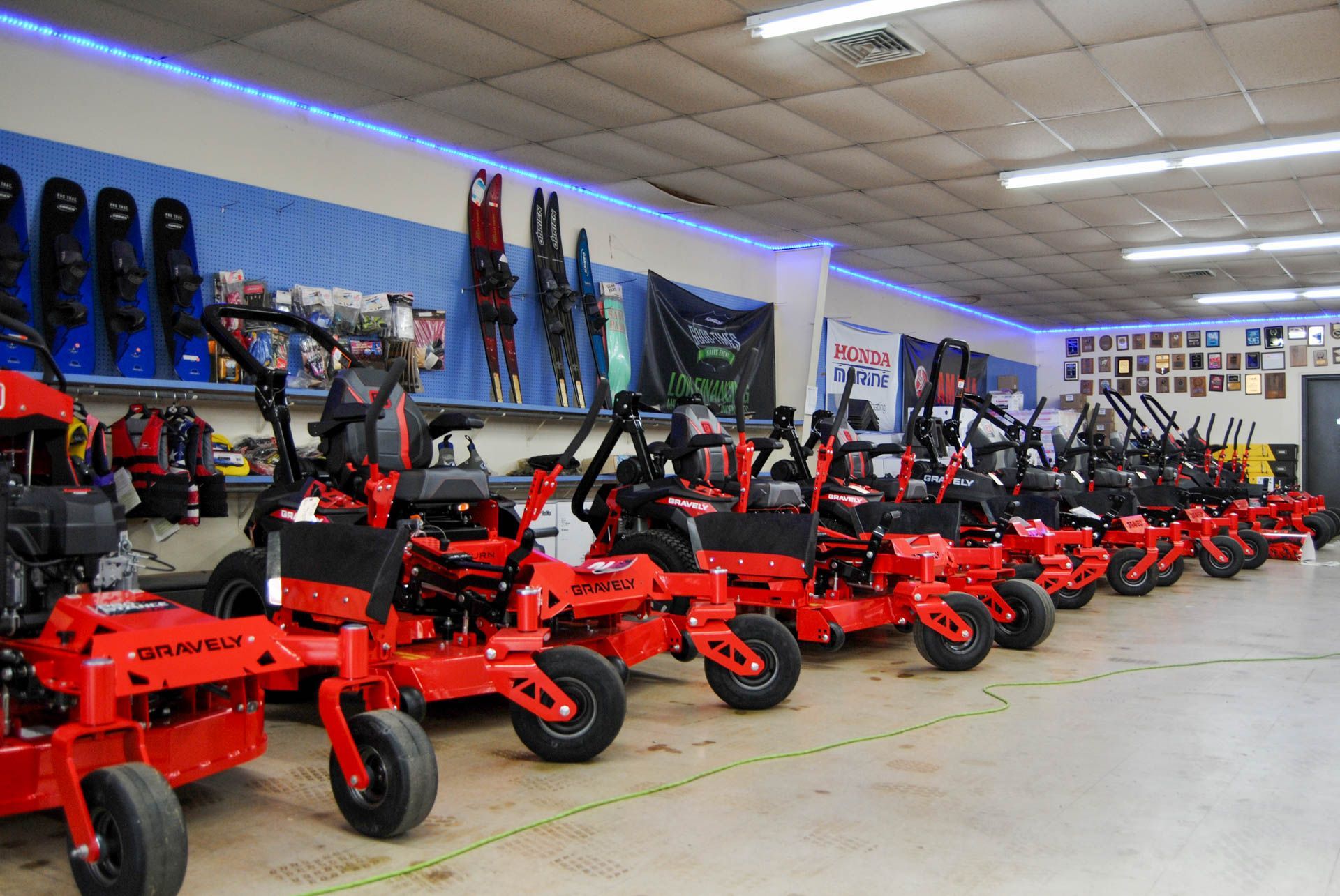A row of red lawn mowers are lined up in a store.