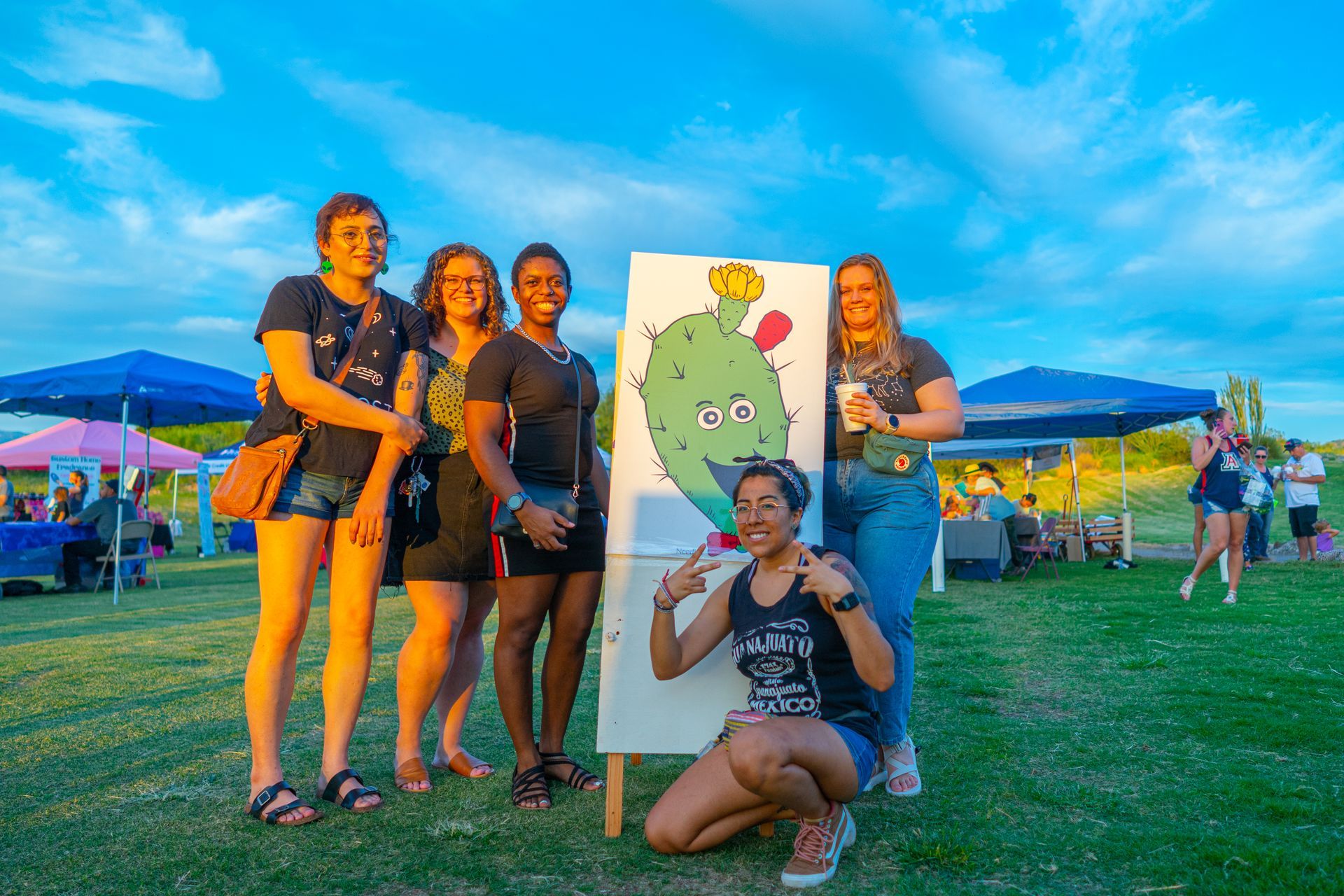 A group of women are posing for a picture in front of a cactus.