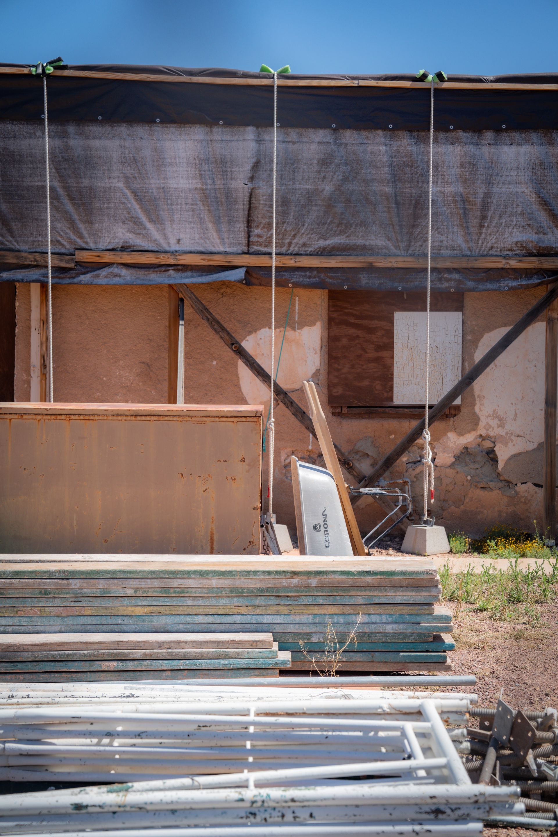 A pile of wood is sitting in front of a building under construction.
