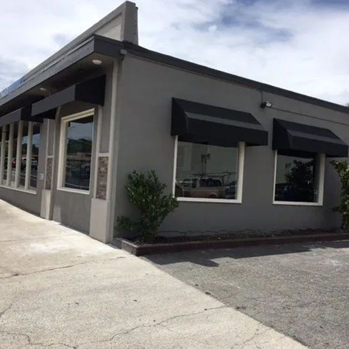 A gray building with black awnings on the windows