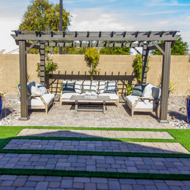 A patio with a pergola , couch , chairs and a coffee table.