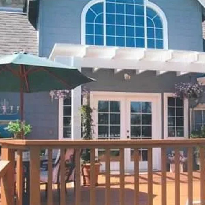 A large house with a deck and umbrellas in front of it.